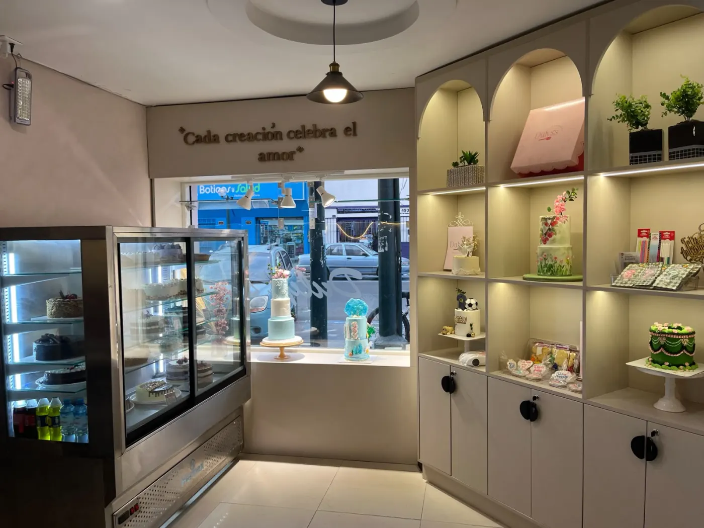Interior de la tienda con vitrinas de tortas y estantes en arco