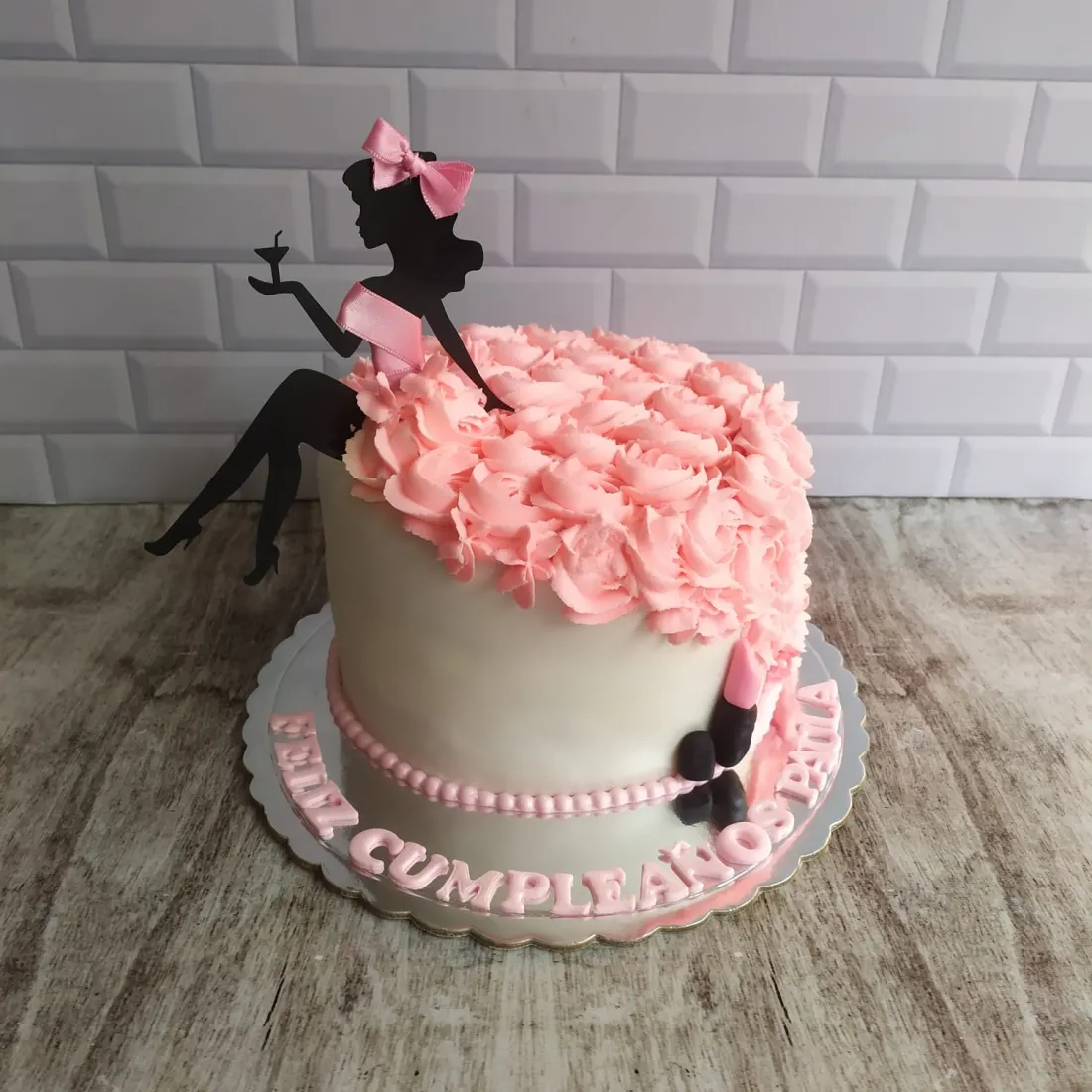 Torta de cumpleaños con silueta de dama y rosetas rosadas